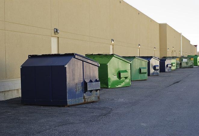 a construction worker unloading debris into a blue dumpster in Coolspring, PA